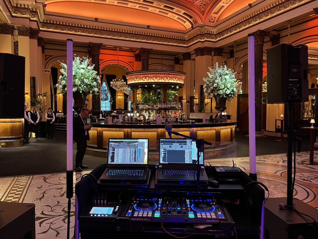 DJ setup with laptops and mixer at The Dome Edinburgh corporate event, warm amber lighting and floral arrangements in background — Premier Disco Scotland