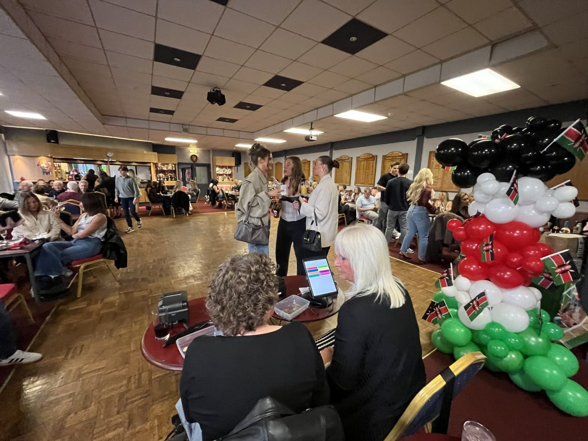 Wide room shot of race night at Sighthill Bowling Club Edinburgh with Kenyan flag balloon display for school fundraiser