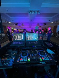 Premier Disco Denon DJ MC7000 console at a live event with guests dancing and purple uplighting in the background