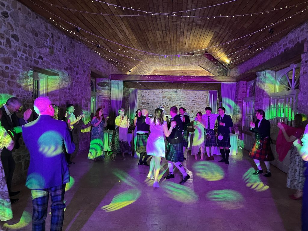 Premier Disco wedding DJ at Colstoun House, East Lothian — packed dance floor with guests in kilts under colourful lighting