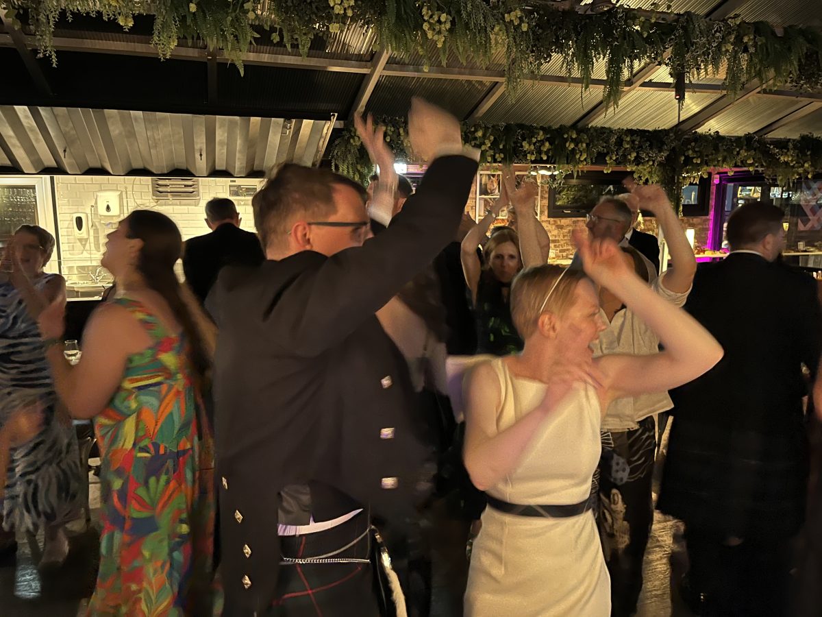 Wedding guests with hands raised on the dancefloor at Stewart Brewing, Loanhead