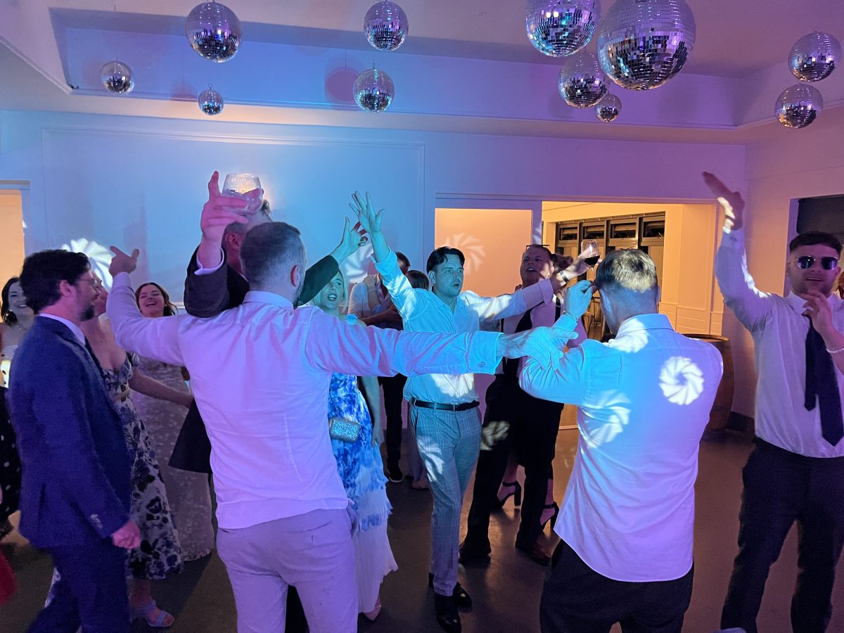 Wedding guests dancing under blue lighting and mirror balls at Whitekirk Hill