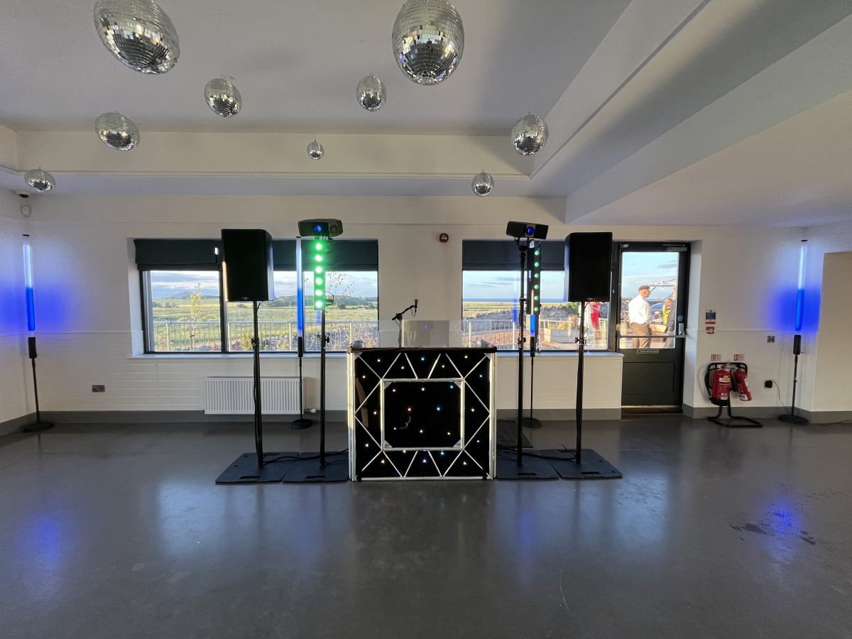 Premier Disco wedding DJ setup at Whitekirk Hill — star-cloth booth, speakers and blue uplighters before guests arrive
