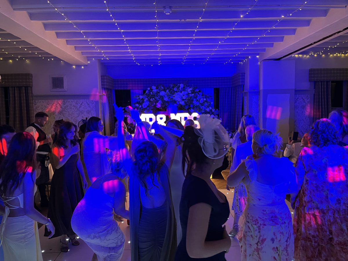 Wedding guests dancing at Stair Arms Hotel, Pathhead, under coloured star lighting